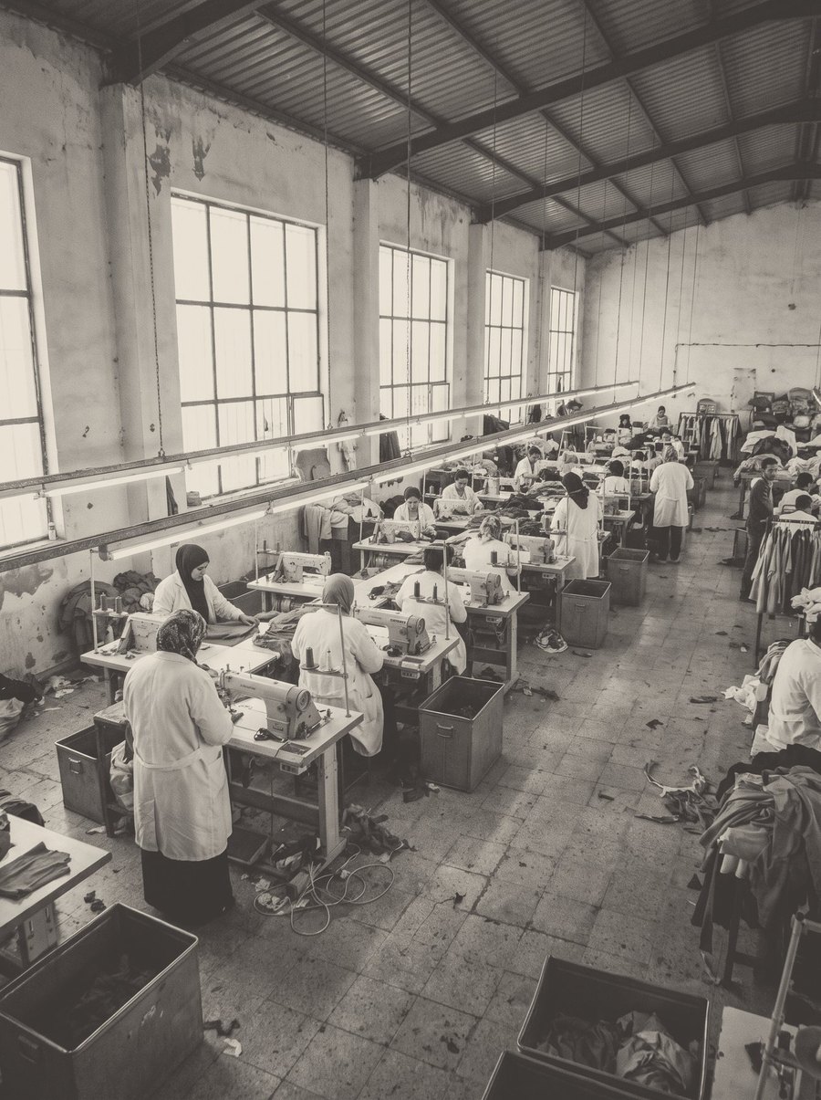 A row of operators at their sewing machines by the windows.